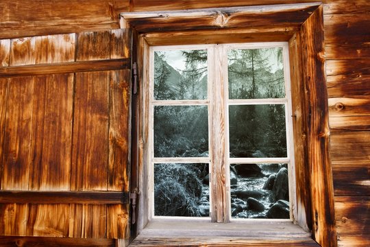 Blick durch das Holzfenster auf den Wildbach in schwarz weiß