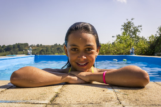 Chica joven descansando sobre el borde de la piscina