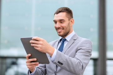 smiling businessman with tablet pc outdoors