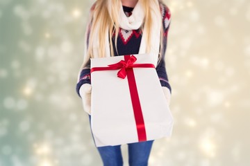 Composite image of festive blonde holding a gift