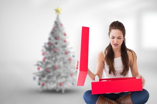 Composite image of unhappy brunette opening present