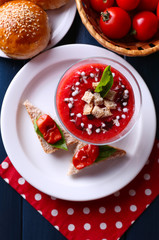 Gazpacho soup in glass bowl, on color wooden background