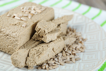 Sunflower halva on plate, on wooden background