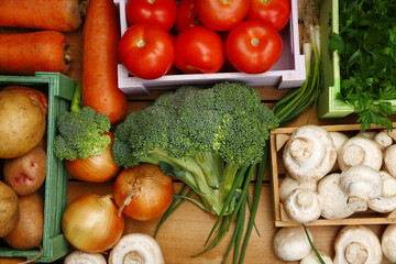 Different vegetables in boxes on wooden background top view
