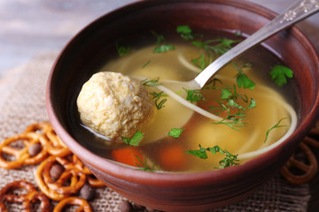 Soup with meatballs and noodles in bowl on wooden background
