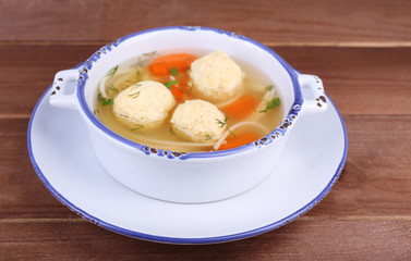 Soup with meatballs and noodles in bowl on wooden background