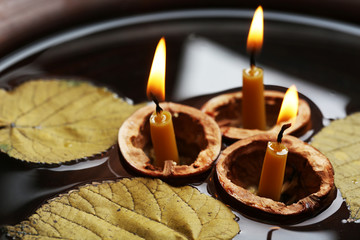 Leaves and three nutshells with candles floating in water