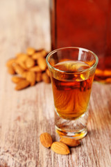 Dessert liqueur Amaretto with almond nuts, on wooden table
