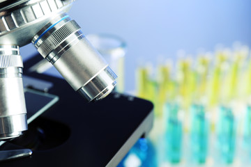 Microscope, grains and test tubes on table, on color background