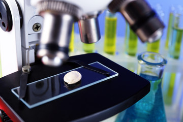 Microscope and laboratory sample, close-up on color background