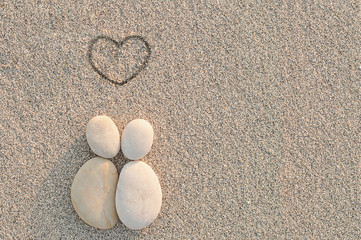 Pebbles shapes lovers with heart on the sand
