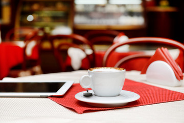 Cup of coffee and tablet computer on table