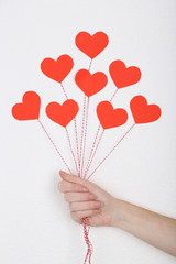 Female hand holding paper balloons, on white wall background