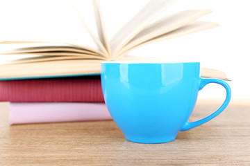 Cup of coffee and open book on wooden surface isolated on white