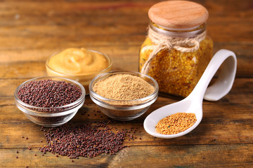 Mustard seeds, powder and sauce in glass jar, bowls and spoon