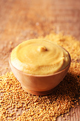 Mustard in bowl on wooden background