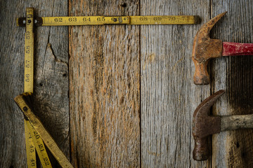 Hammers and Measuring Tape on Rustic Old Wood Background
