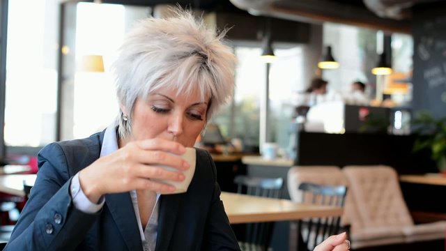 business middle aged woman drinks coffee in cafe - closeup
