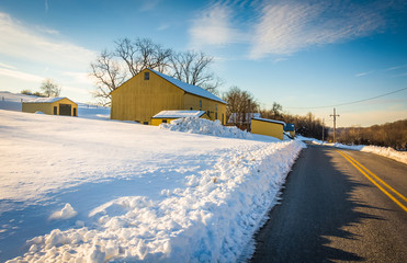 Yellow barn and a snow covered field along a country road in Yor