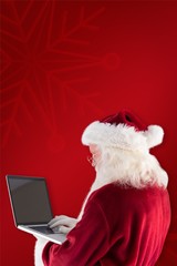 Composite image of santa claus uses a laptop