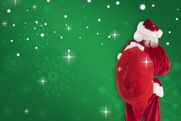 Composite image of santa is holding his bag in one hand