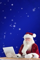 Composite image of santa pays with credit card on a laptop
