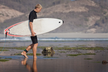 Surfer with surfboard on the beach