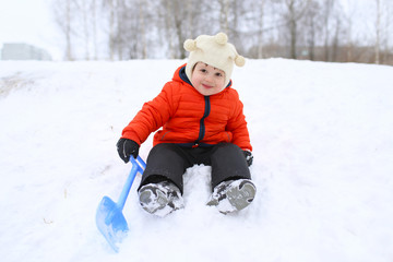 Fototapeta na wymiar lovely 2 years toddler with shovel in winter