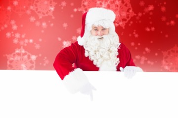 Composite image of joyful santa claus presenting sign