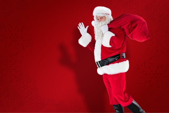Composite image of santa holding a sack and waving