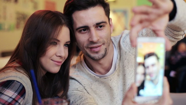 couple taking selfie photo with cellphone sitting in cafe
