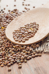 Organic lentils with wooden false on burlap background