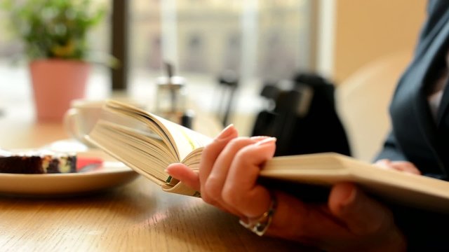 woman reads a book in cafe - urban street with cars
