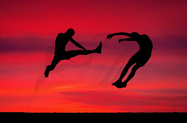 Fototapeta na wymiar Silhouettes of two fighters on sunset fiery background.