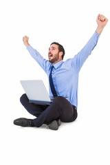 Excited cheering businessman sitting using his laptop