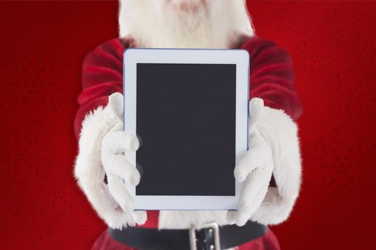 Composite image of santa presents a tablet pc