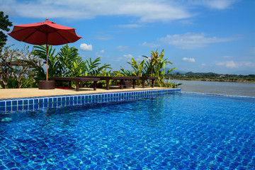 Swimming pool with daybed and red umbrella  in Chiangrai ,Thaila