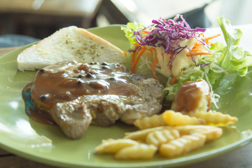 Grilled pork chop with chips and vegetables.