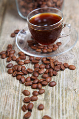 Transparent cup of coffee and coffee beans with the bank
