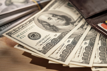 Brown Wallet with credit cards and dollar banknotes over wooden