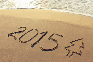 Fototapeta na wymiar 2015 year written on sandy beach. Toned image