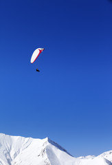 Fototapeta na wymiar Paraglider in snowy mountains at nice sun day