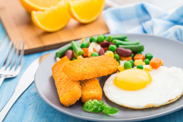 Fish sticks, fried egg and vegetables