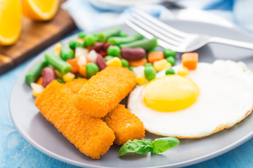 Fish sticks, fried egg and vegetables