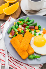 Fish sticks, fried egg and vegetables
