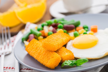 Fish sticks, fried egg and vegetables