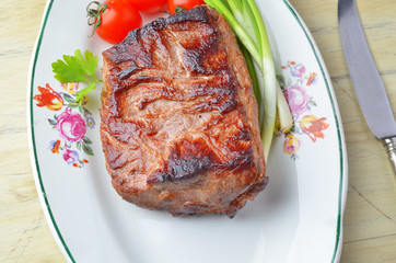 Roast beef  and vegetables on a plate on a wooden table