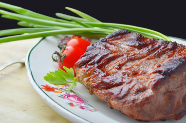 Roast beef  and vegetables on a plate on a wooden table