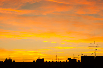 Urban sunset  rooftops antenas and clouds