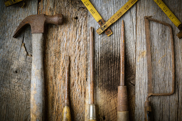 Hammer, Screwdriver, Hand Saw and Tape Measure on Rustic Wood Ba